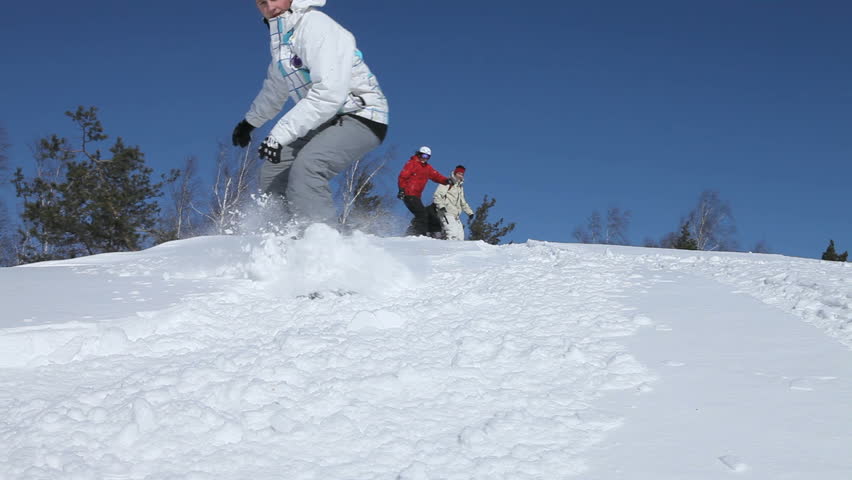 Four young people snowboarding down the hill