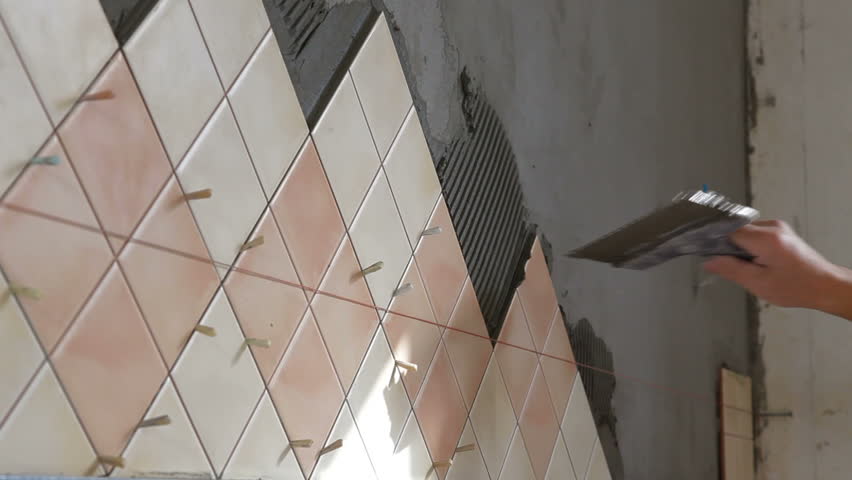Man's hands Installing Ceramic Tile to a Kitchen wall, Close-up