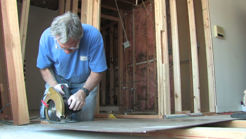 Man uses a power saw to cut wood.