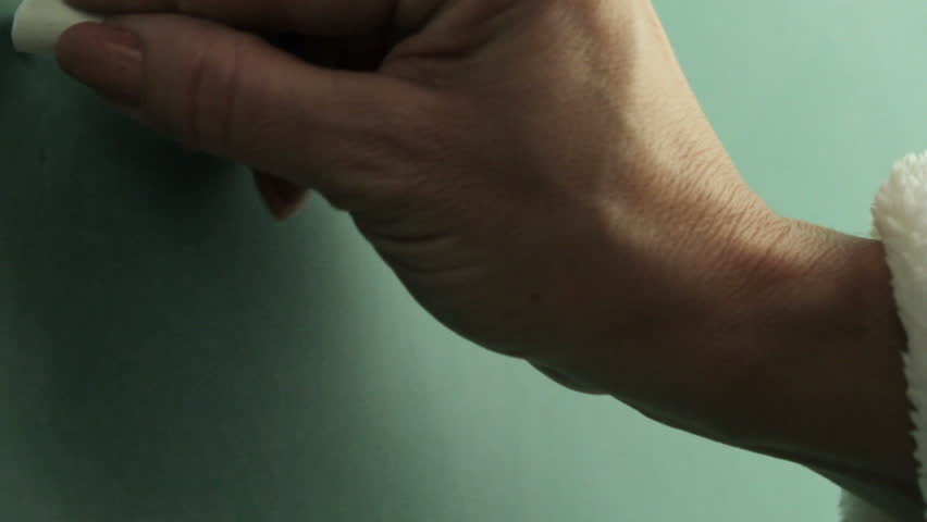 A hand writes the word education, then the word teach on a chalkboard