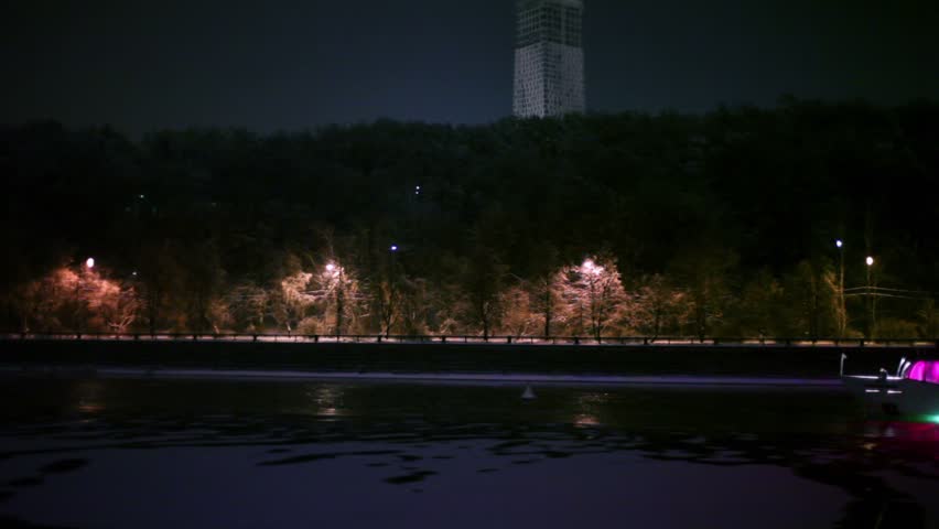 Ship decorated with garlands, floats down the river at winter night