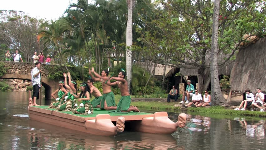 Polynesian Cultural Center in Laie Oahu Hawaii. Canoe show with dancers from New Zealand. Green clothes. Demonstration for tourists in the main lagoon.  Water, lagoon and palm trees.