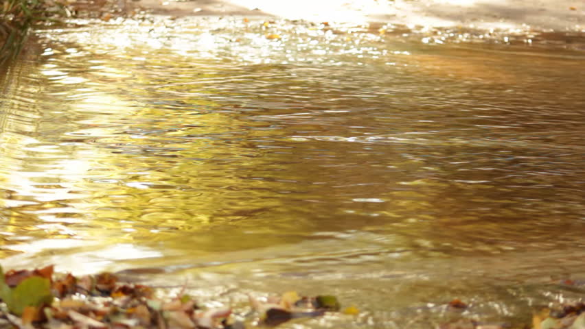 The waters of Oak Creek in Sedona, Arizona ripple rapidly over a concrete area as the fall leaves are reflected.