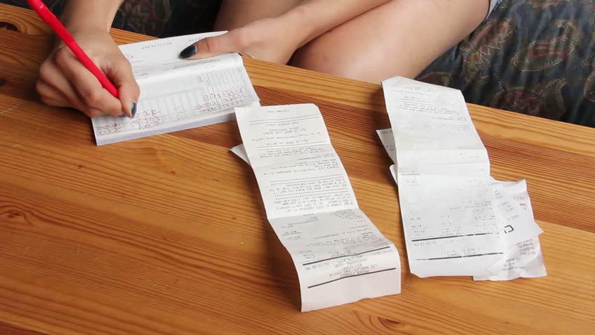 Woman writes notes on checkbook from receipts