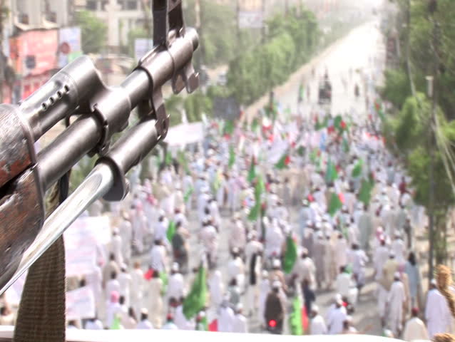 KARACHI, PAKISTAN - MAY 6: A nervous police guard watches over a rally of Islamic extremists as they gather in protest over the killing of Osama Bin Laden in Karachi, Pakistan on May 6, 2011.