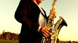 man playing jazz on golden saxophone in nature