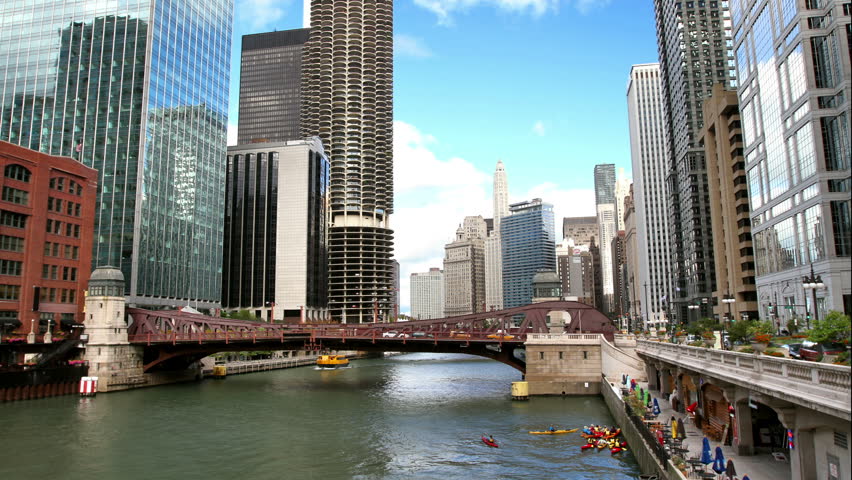 A time lapse of the Chicago River, surrounded by skyscrapers, with boats passing by