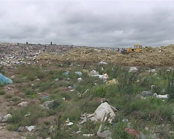 Garbage handling equipment and homeless people looking for food and survival items in dump. Environmental pollution. Poverty. 