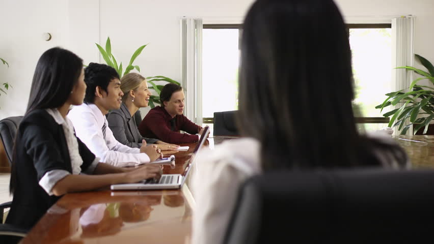 Attractive young Asian business woman smiling at business meeting with co-workers. Rack focus