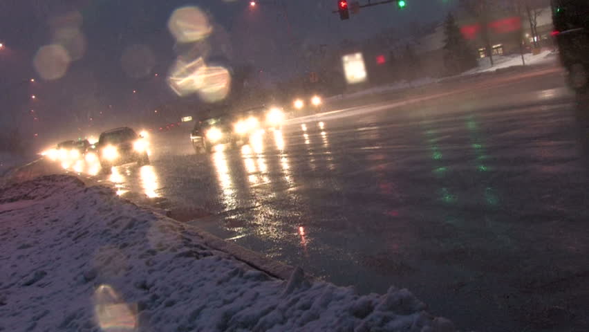 Canted angle of rush hour traffic coming home at night in a blizzard 