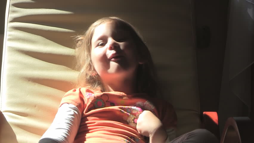 Happy girl makes faces on rocking chair