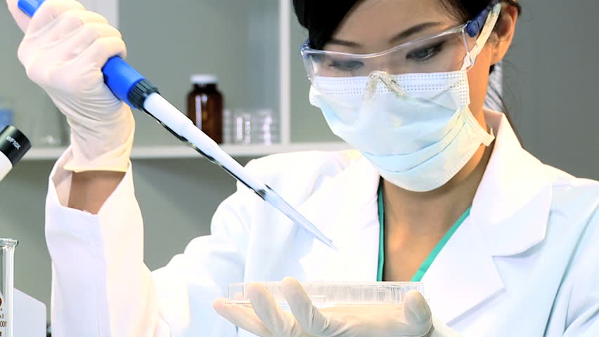 Medical research student using a laboratory pipette and petri dish