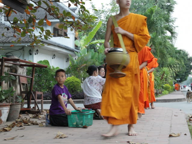 LUANG PRABANG, LAOS - OCTOBER 27: Two women give sticky rice to monks during the morning procession on OCTOBER 27, 2011. 