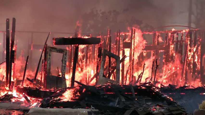 Remnants of a disastrous house fire leaves only the support beams standing and those not for long.
