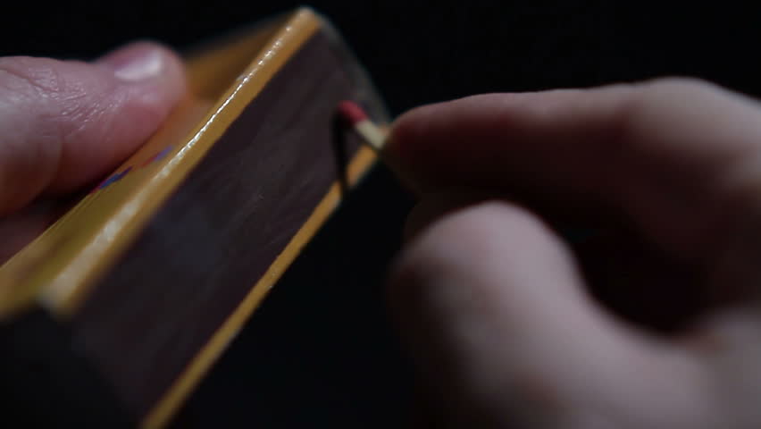 Close up of hands lighting a match.