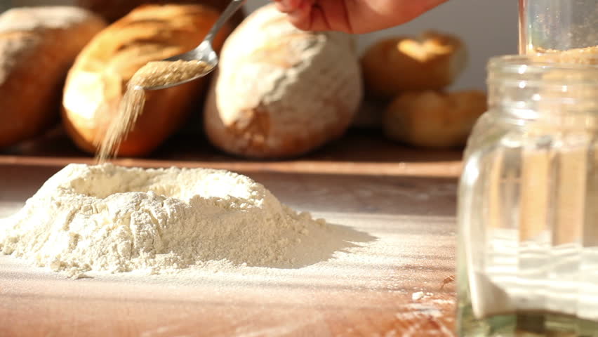 Baker adding ingredients to flour on table 