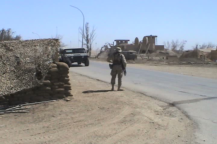IRAQ - CIRCA MAY 2003: Checkpoint at Talil, mileage signs on post to Wrigley Field and Atlanta, soldier holding weapon in back of humvee with Baghdad Mosque in Background.