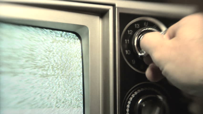 Static TV, Man (30s) turning channel knob on retro television stuck on static
