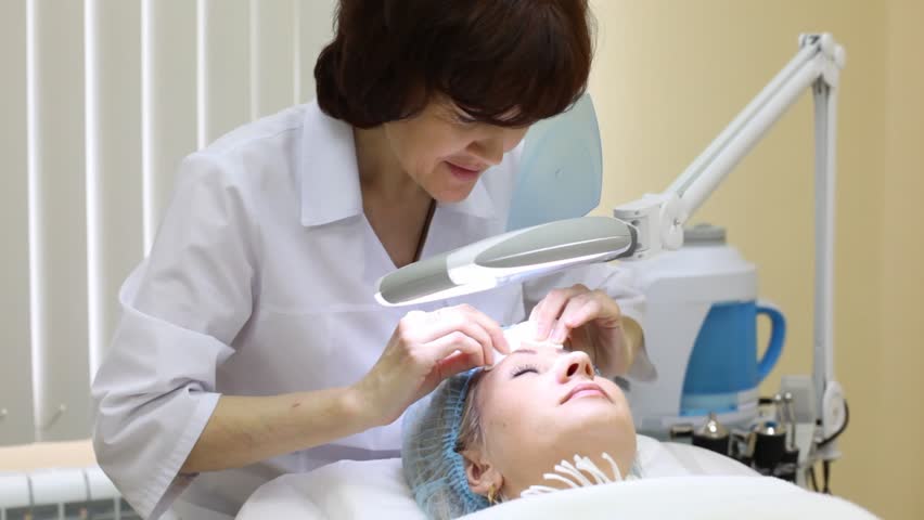 Cosmetician does disinfection of face after cosmetic procedures to client