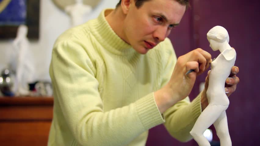 Sculptor corrects armless female figurine by file, then watch on it and polishes