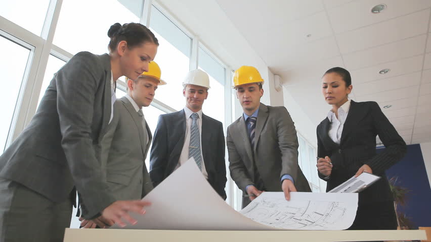 Three businessmen or engineers in hardhats discussing a new project