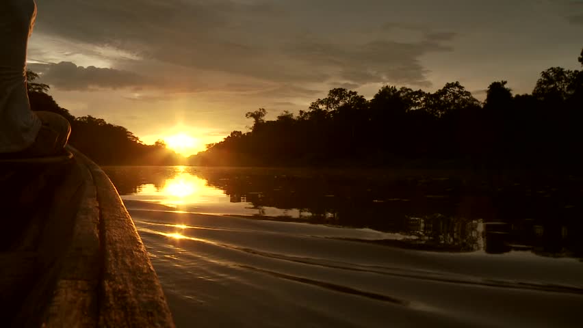 Paddeling With Canoe On The Amazon River in front of the sunset, South America, Peru