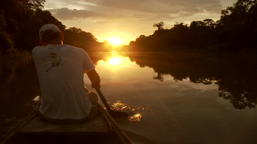 Paddeling With Canoe On The Amazon River in front of the sunset, South America, Peru
