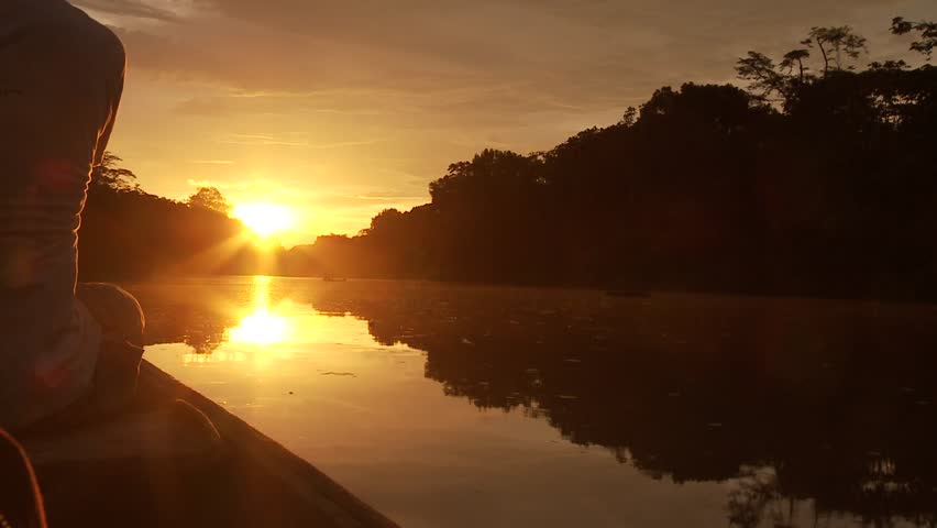 Paddeling With Canoe On The Amazon River in front of the sunset, South America, Peru