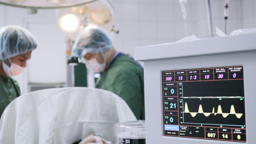 Anesthesia machine in use. Out of focus surgeons at the background.