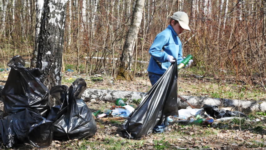 little boy collecting trash with black bag in park at spring