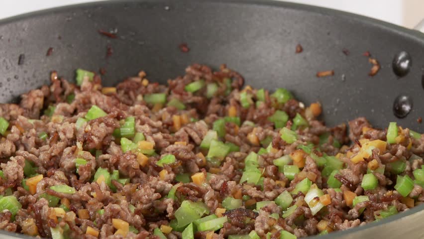 Minced meat being mixed in a pan with diced vegetables