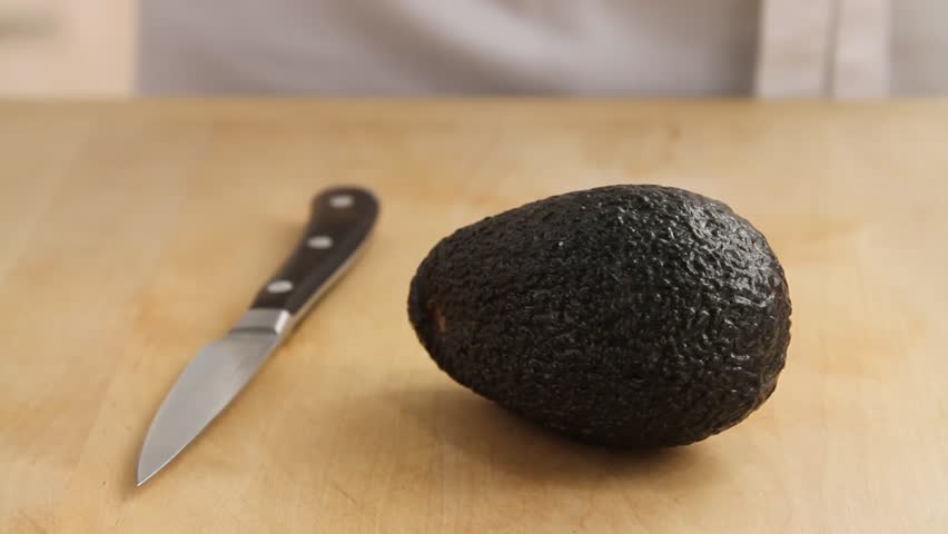 An avocado being halved and peeled