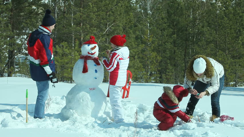 Happy family of four painting the snowman made not far from winter forest