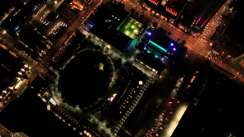 Aerial night vertical view of skyscraper rooftops and illuminated streets in a modern city