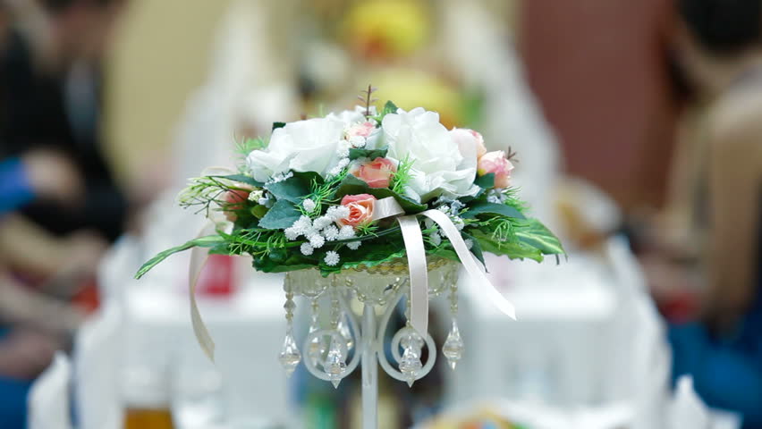 Flower arrangement on the wedding diner table in the background guests