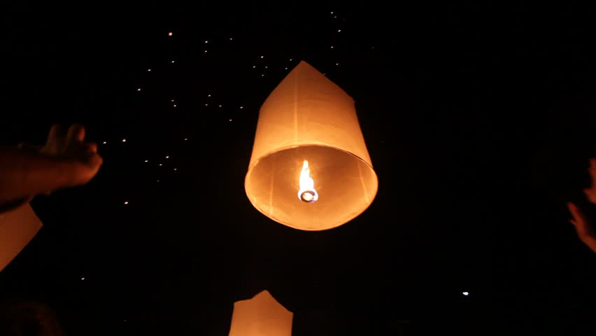 people launching traditional fire lantern during Loi Krathong festival in Chiang Mai, Thailand