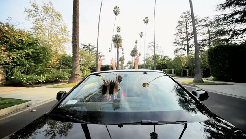 Two females driving luxury convertible