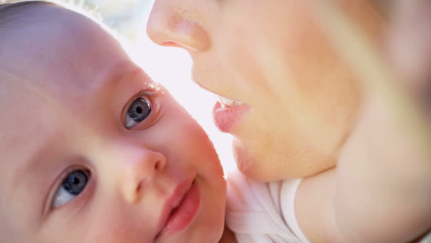 Close up of a young mother holding her baby while he plays with her hair