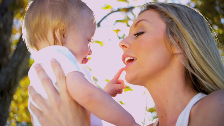 Beautiful young mother outdoors tenderly holding her baby son