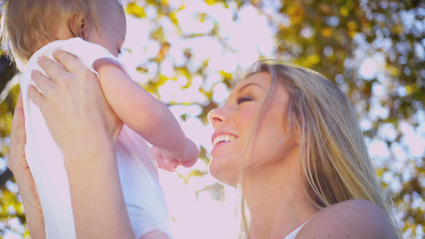 Beautiful young mother in close up outdoors tenderly holding her baby son