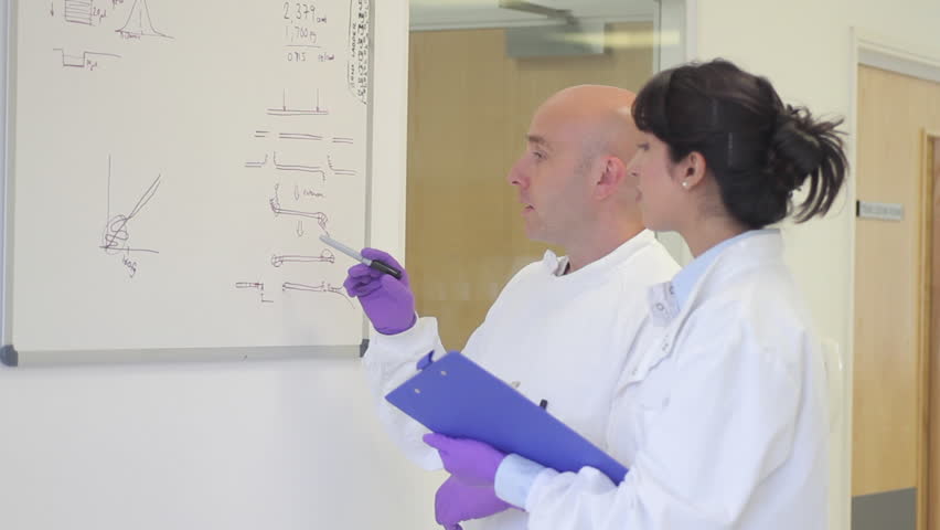Scientist analyze and discuss research data on white board in science laboratory