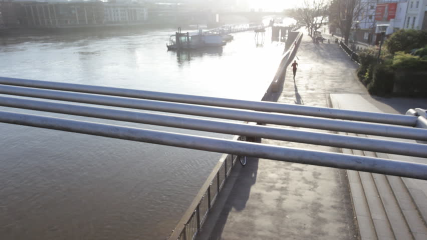 Runner on embankment under millenium bridge, London, UK