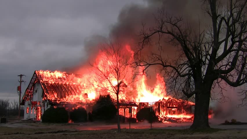 25 minutes into this blazing house fire the rafters of the roof are all exposed while fire and smoke shoot high into the air.