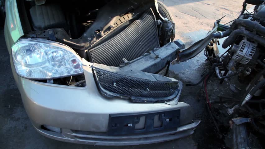 Two crashed cars stand on junkyard, closeup view in motion