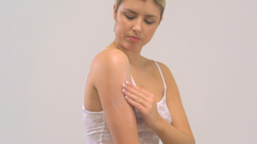 MEDIUM CLOSE UP PAN OF A YOUNG WOMAN MOISTURIZING ON WHITE BACKGROUND