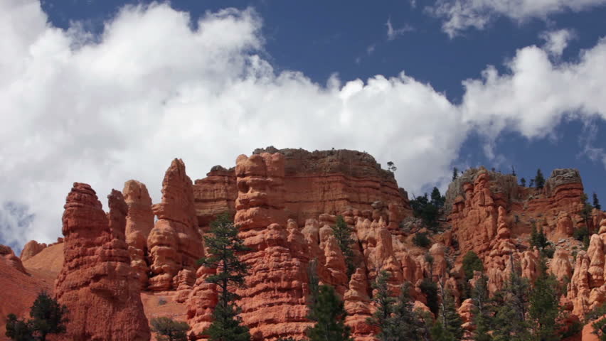Bryce Canyon National Park in southern Utah. Fluffy clouds above red rock mountain peak. Natural landscape erosion and grand canyons with stunning rock formations.