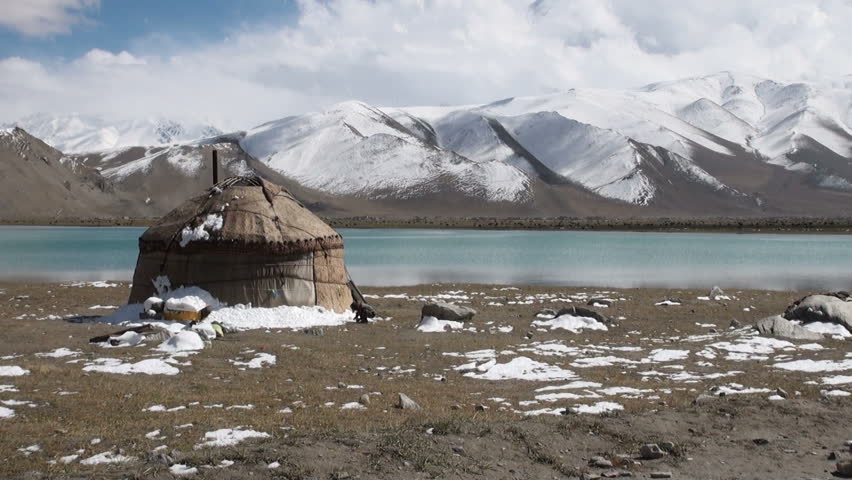 A boy plays in front of a yurt alongside Karakul lake, China