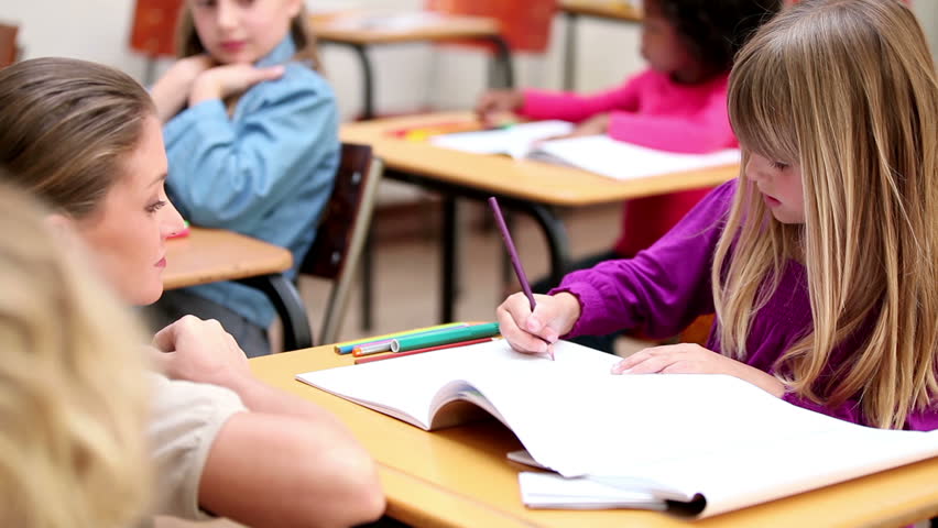 Teacher helping her pupil in the classroom