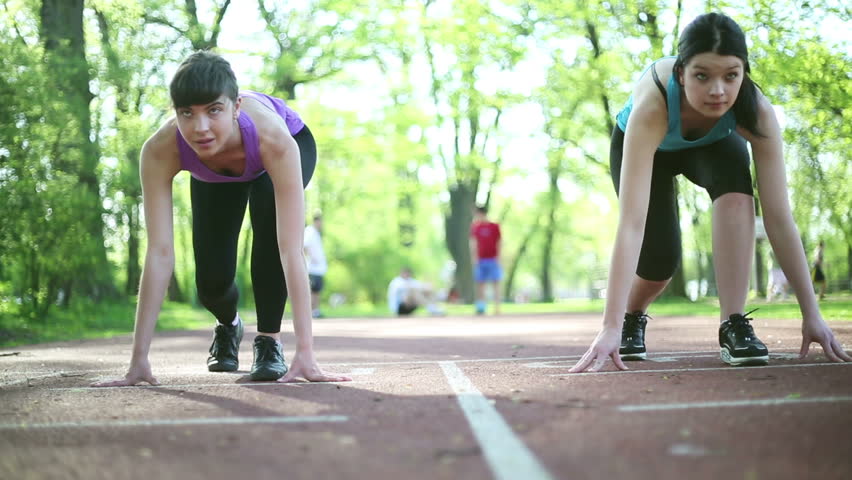 Two young beautiful women preparing to run, dolly shot

