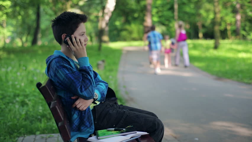 Young boy talking on cellphone in the park
